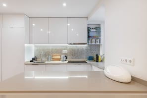 A modern kitchen with white cabinets, a stainless steel sink, a kettle, a toaster, and a built-in oven. - Rossio Boutique Apartment 2 (Lisbon)