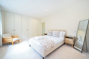 A bedroom with a bed, a bedside table, a chair, a wardrobe, and a mirror. - Willow Lodge 5,800 SQFT Quiet Luxury Living - Pass the Keys (Elstree)
