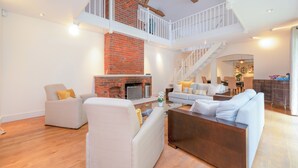 A spacious living area with a fireplace, a staircase, and a dining area. - Willow Lodge 5,800 SQFT Quiet Luxury Living - Pass the Keys (Elstree)