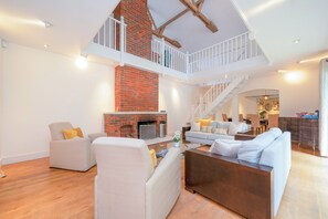 A spacious living area with a fireplace, a staircase, and a dining area. - Willow Lodge 5,800 SQFT Quiet Luxury Living - Pass the Keys (Elstree)