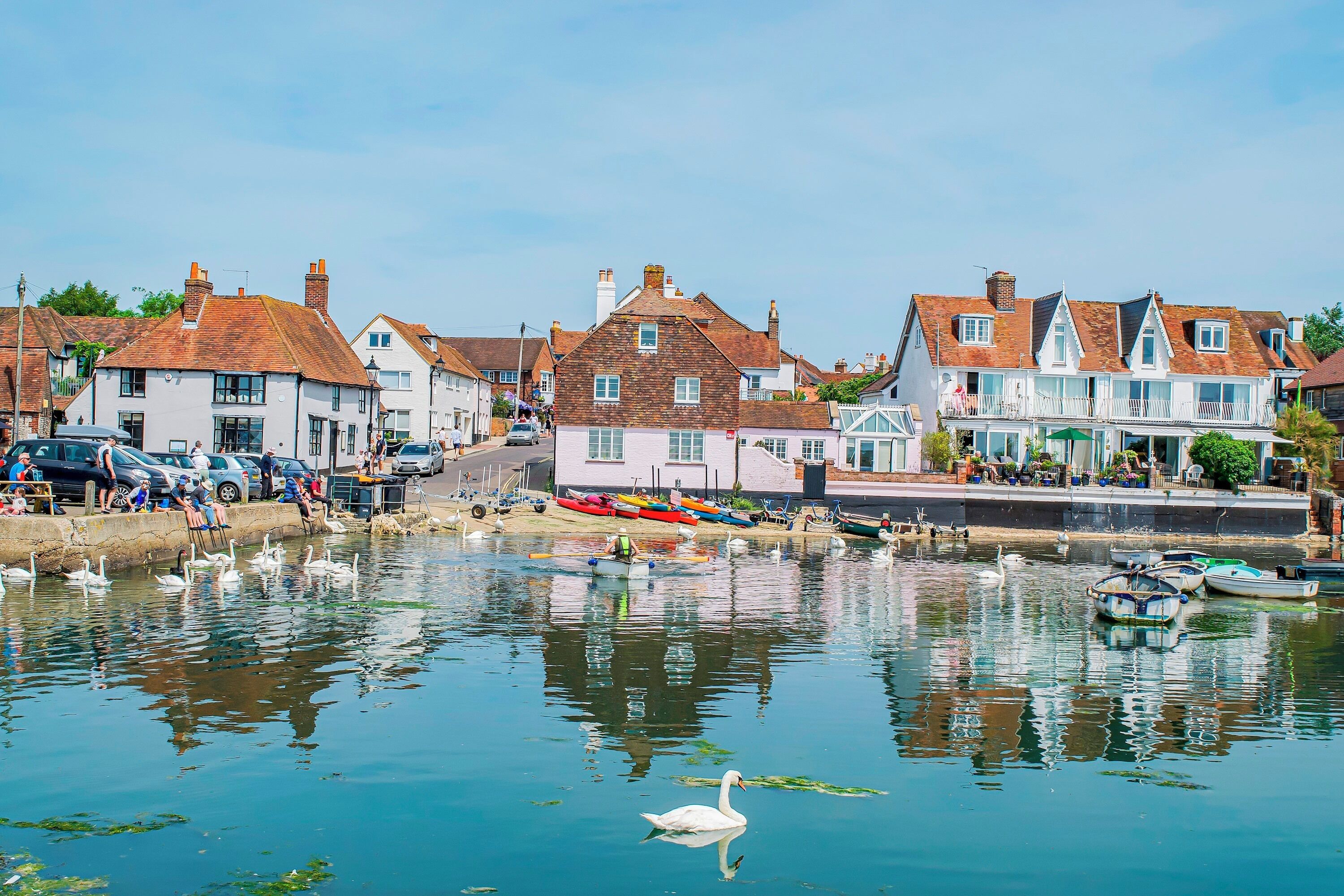 Une ville située au bord de l’eau, avec des bâtiments, des bateaux et un cygne.