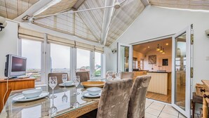 A dining area with a glass table, chairs, and a television. - Stunning Emsworth Family Home - Pass the Keys (Emsworth)