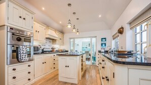 A spacious kitchen with white cabinetry, a central island, and a view into the dining area. - Stunning Emsworth Family Home - Pass the Keys (Emsworth)