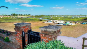 A coastal view with boats docked along the shore, a brick wall, and a grassy area. - Stunning Emsworth Family Home - Pass the Keys (Emsworth)