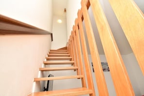 A wooden staircase with a handrail, leading to a landing with a picture of a beach scene. - Residenz Arcobaleno Two-Room Apartment Cavalluccio Marino for 6 People (Chioggia)