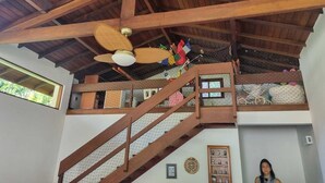 Una estructura de madera de varios niveles con ventilador de techo, escalera y balcón con vistas.