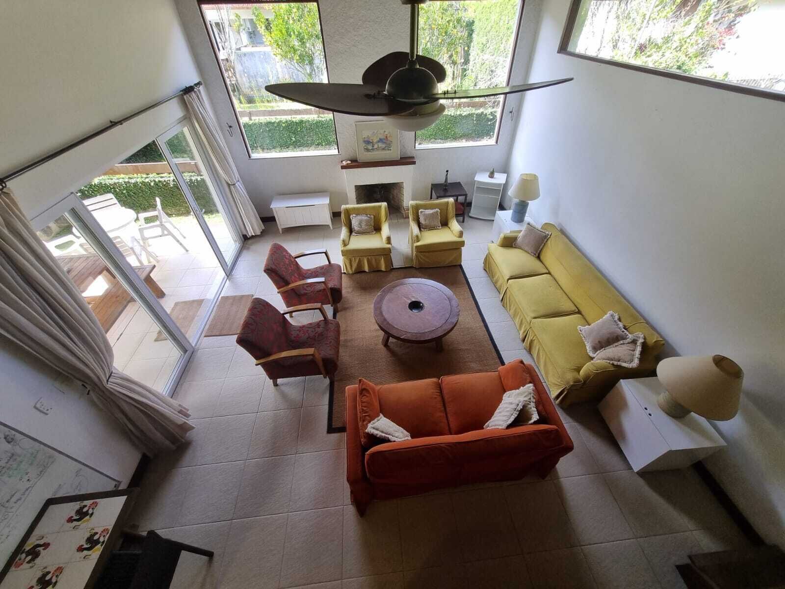 A spacious living room with a large window, a ceiling fan, and a yellow sofa.