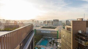 En høj bygning med en pool på taget, udsigt over bybilledet og et skilt for Allianz Bank.
