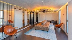 En moderne hotellobby med et centralt siddeområde, en lysekrone og en glasvæg.