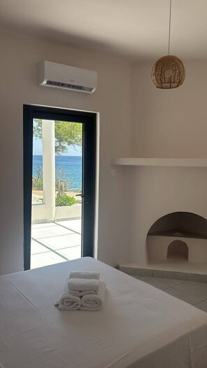 Un dormitori amb un llit, una porta que dona a una zona exterior, un aparell d'aire condicionat i una làmpada penjant.
