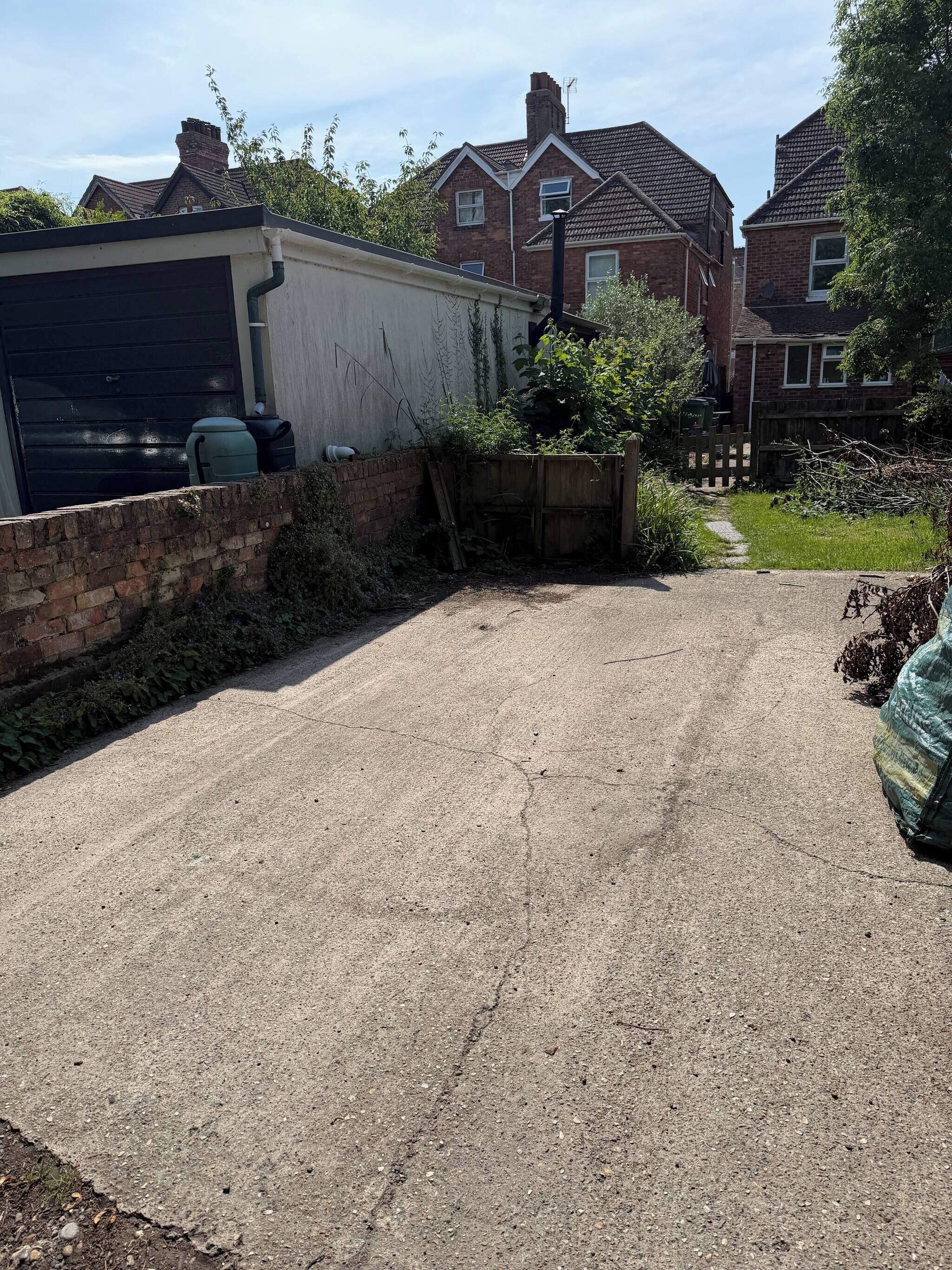A residential driveway with a garage, a brick wall, and a wooden fence.