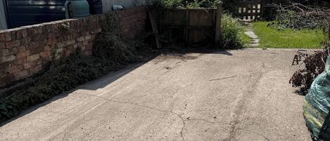 A residential driveway with a garage, a brick wall, and a wooden fence.