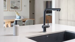 Cozinha moderna com ilha central, pia preta e design minimalista.