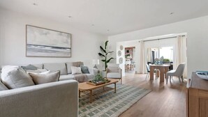 Uma sala de estar moderna com sofá, mesa de centro e área de jantar.