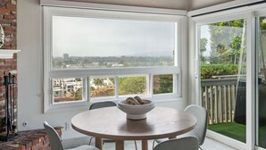 Um quarto com uma janela grande, uma mesa redonda com cadeiras e vista para a cidade.