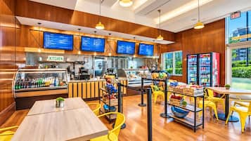 A restaurant interior with wooden paneling, yellow chairs, a counter with a coffee machine, and a menu display.