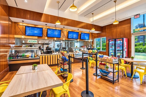 A restaurant interior with wooden paneling, yellow chairs, a counter with a coffee machine, and a menu display.
