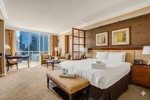 A hotel room with a large bed, a desk, a chair, a small table, and a balcony with a view of the city. - Luxury Studio | MGM Signature | Sleeps 4 | Strip View | No Resort Fee (LAS VEGAS)