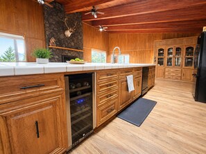 Eine Küche mit Holzausbau, einer Steinwand, einem aufgehängten Hirschgeweih und einem Weinkühler.