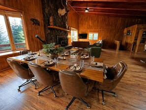 A wooden interior with a dining table set for six, a fireplace, and a stone wall. - Family-Friendly Cabin with Filtered Lake Views, Bunk Rooms, Game Space & Deck. (Cascade)