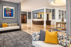 Eine moderne Hotelhalle mit Empfangstresen, einer Sitzecke und einem großen gerahmten Kunstwerk.