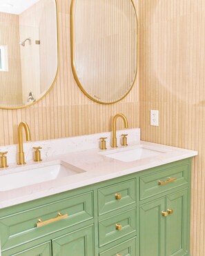 A bathroom with two sinks, gold faucets, green cabinets, and two round mirrors. - Fully Renovated 3 Bedroom Home in Prestigious Toluca Lake (Los Angeles)