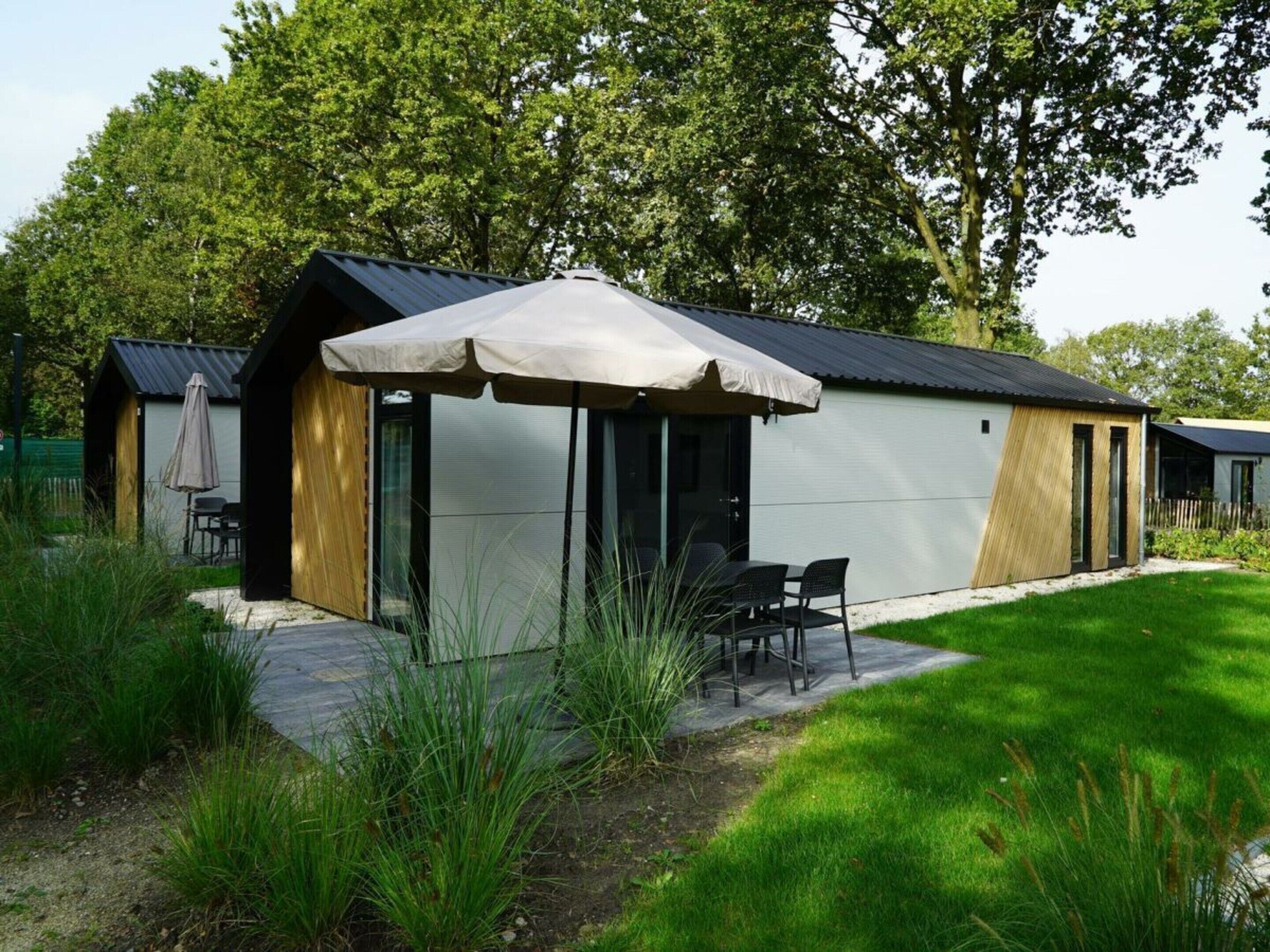 A modern building with a covered patio, outdoor seating, and a pathway leading to the entrance.