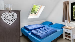 A bedroom with a skylight, two beds with blue bedding, a dresser, and a window with curtains. - Restyled Koningshoeve 4 People (Schoorl)