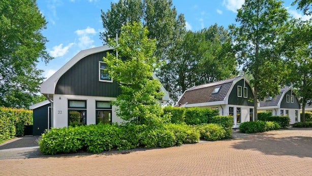 A modern building with a curved facade, a paved driveway, and surrounding greenery. - Restyled Koningshoeve 4 People (Schoorl)