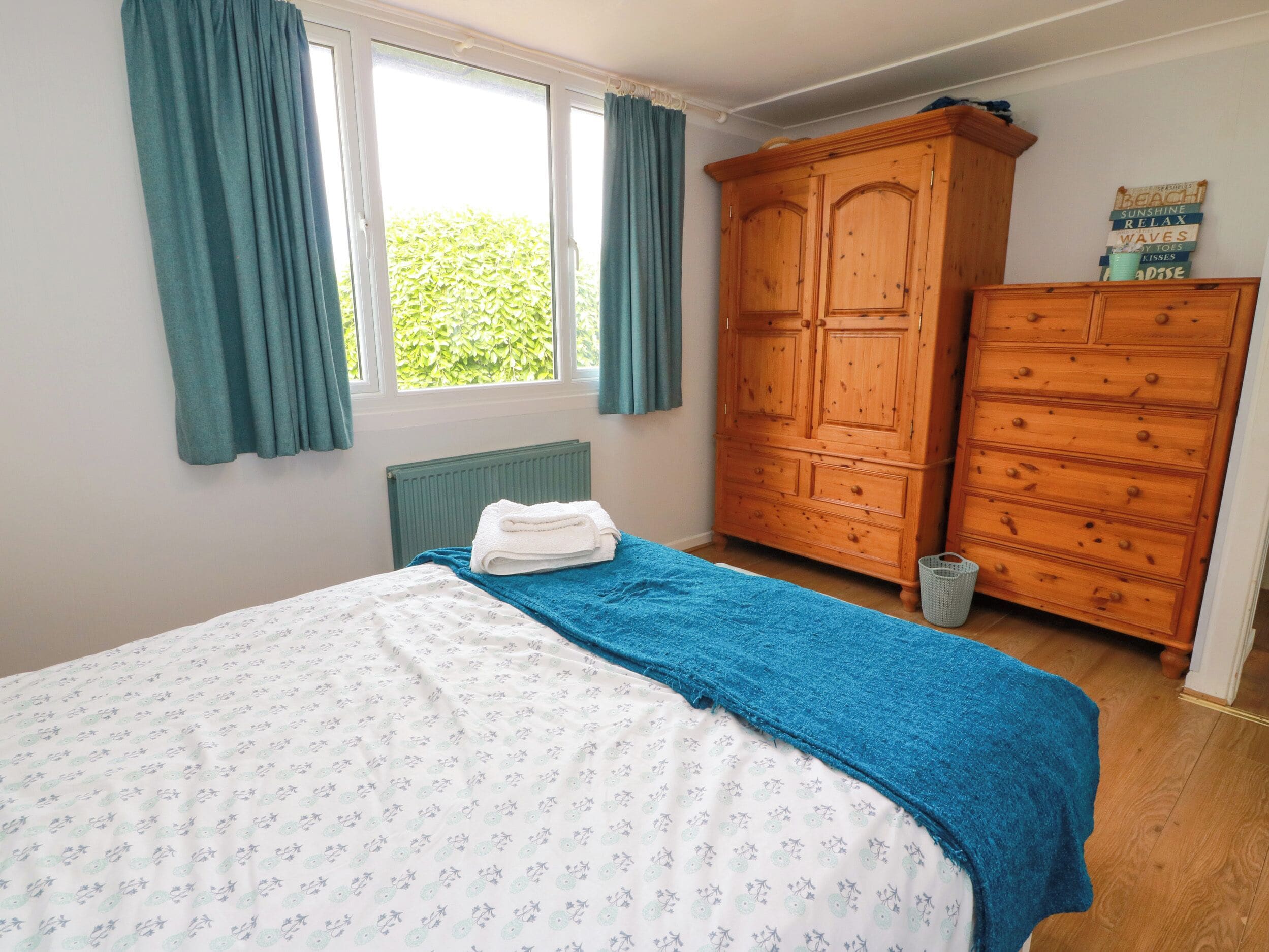 A bedroom with a bed, a wardrobe, and a window with curtains.