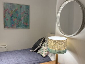 Een slaapkamer met een bed, een spiegel aan de muur en een schilderij.