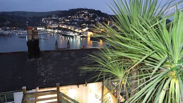 Un pueblo costero al atardecer con un puerto deportivo, una escalera de madera y una planta de palma.