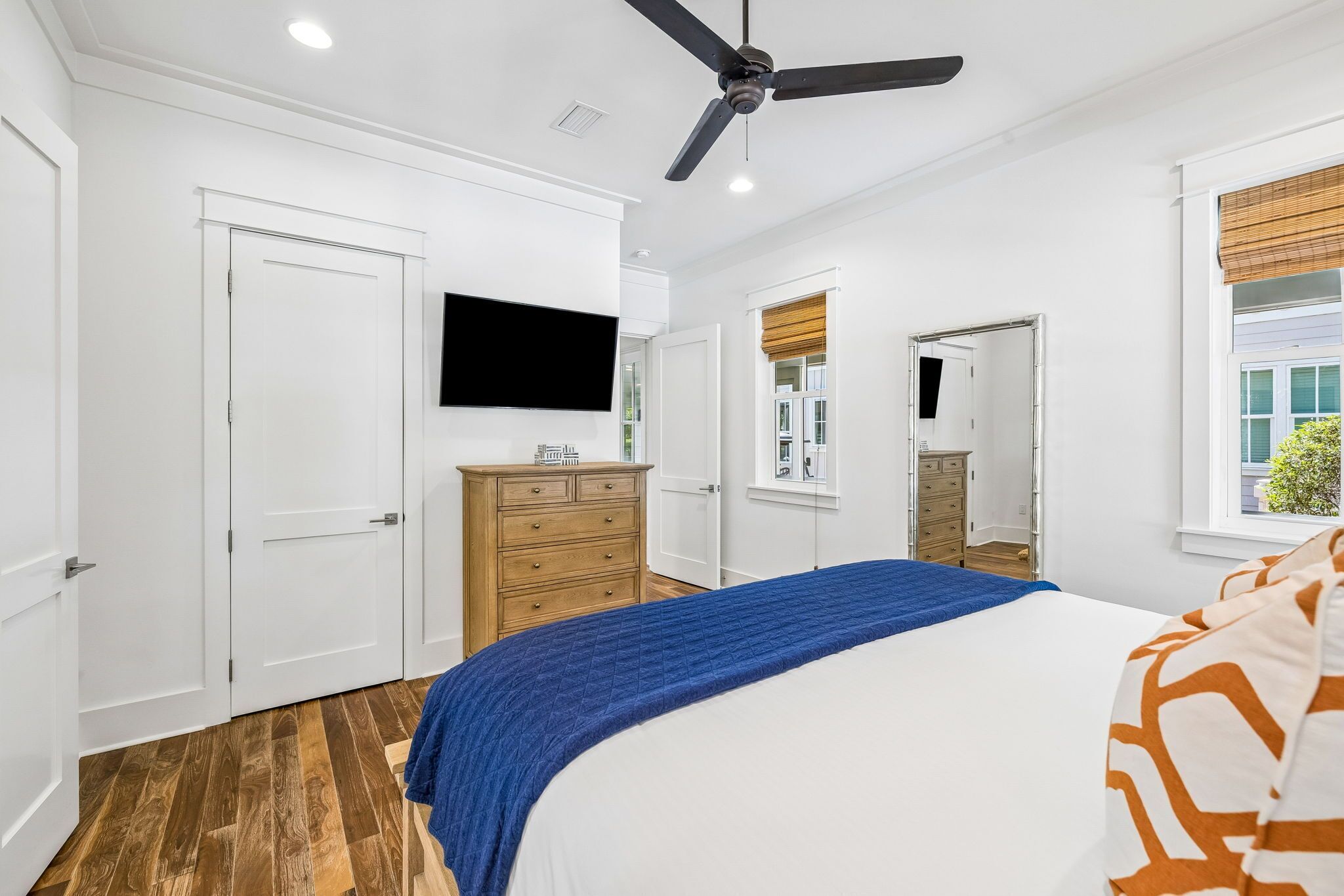 A bedroom with a bed, a dresser, a television, and a ceiling fan.