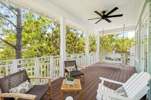 A covered porch with wooden furniture, a ceiling fan, and a view of trees. - WaterColor Escape with Pool and Screened-in Porch (Santa Rosa Beach)