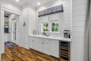 A modern kitchen with white cabinetry, a built-in oven, and a coffee maker. - WaterColor Escape with Pool and Screened-in Porch (Santa Rosa Beach)
