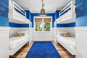 A room with bunk beds, a blue carpet, and a window with blinds. - WaterColor Escape with Pool and Screened-in Porch (Santa Rosa Beach)