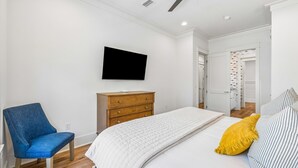 Ein Schlafzimmer mit einem Bett, einem Sessel, einer Kommode, einem Fernseher und einem Deckenventilator.