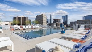 Ein Pool auf dem Dach mit Liegestühlen und Blick auf die Stadt.