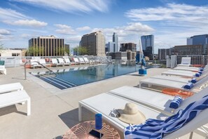 Ein Pool auf dem Dach mit Liegestühlen und Blick auf die Stadt.