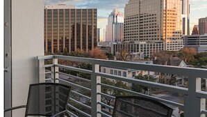 Ein Balkon mit Blick auf die Stadt, Metallstühle und einem Geländer.