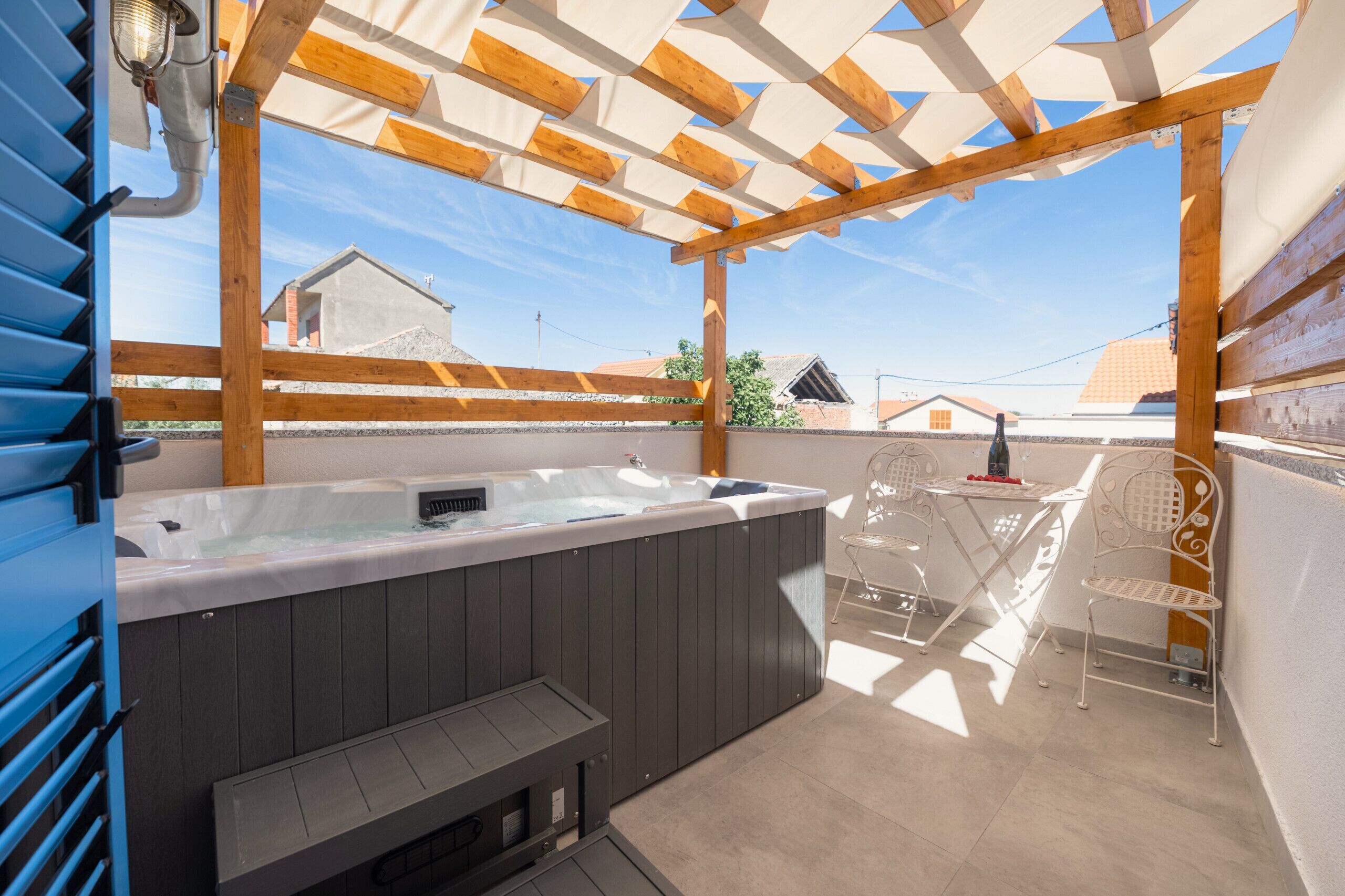 Un jacuzzi bajo una pérgola de madera con vistas a edificios.