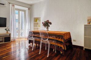 A dining area with a table, chairs, a vase with flowers, and a TV. - Garibaldi 44 - Milan Most Vibrant District (Milano)