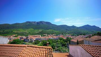 Un villaggio con edifici a tetto di tegole, una montagna sullo sfondo e un cielo sereno.