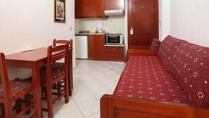 A compact living space with a kitchenette, a dining table with chairs, and a sofa.