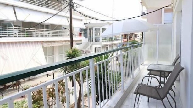 A balcony with a table and chairs, a railing, and a view of buildings and greenery.