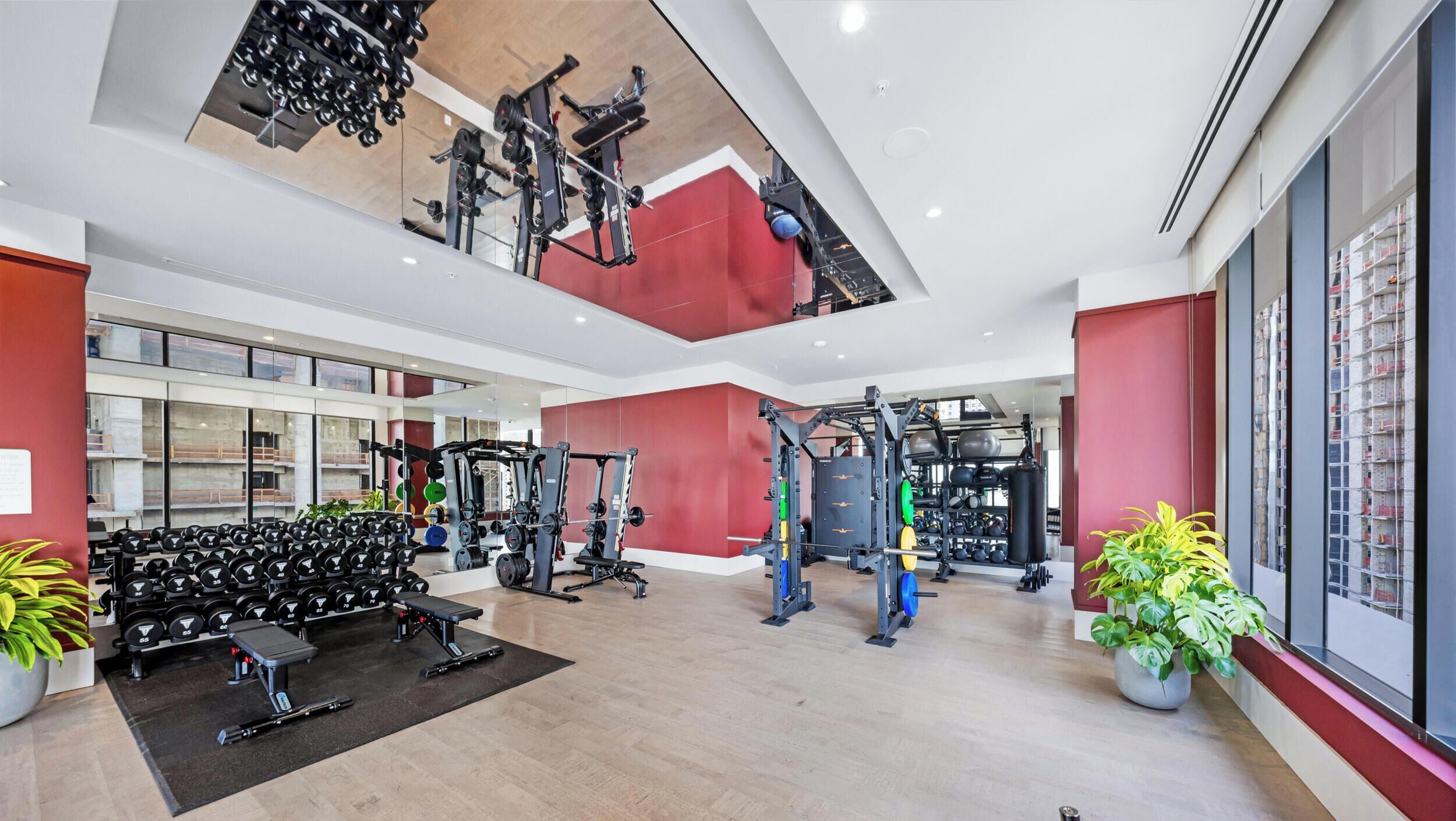 A modern gym with various weightlifting equipment, a bench, and dumbbells.