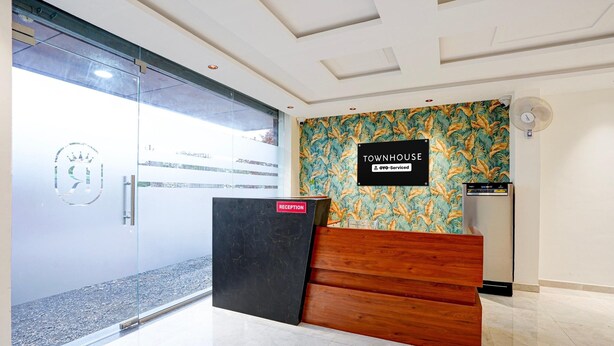 Zona de recepción con mostrador, señalización que indica servicio de OVO y pared decorada con motivos de hojas tropicales.
