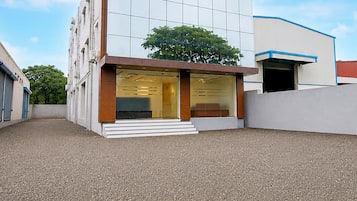 A modern building with a glass facade, a set of steps leading to the entrance, and a tree in the background.