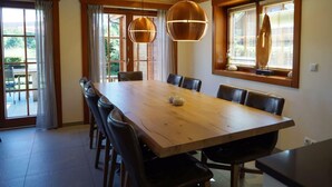 A dining area with a wooden table, leather chairs, pendant lights, and a view through large windows. - Boekhorst L"etage 10 (Lochem)