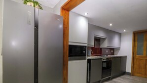 Una cocina moderna con refrigerador, microondas, horno y gabinetes de madera.
